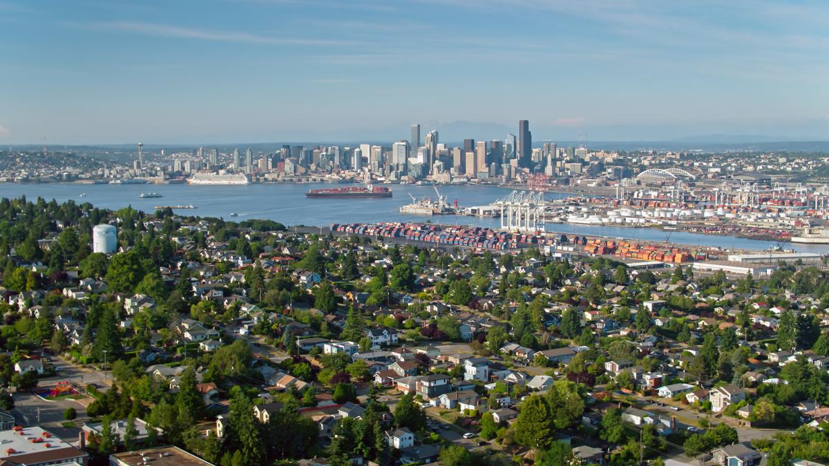 Aerial shot of Seattle, Washington on a sunny afternoon in summer, taken from above residential streets in West Seattle and looking across the bay towards the port and the downtown skyline